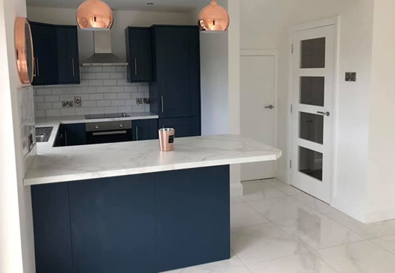 Navy kitchen cabinets and breakfast bar with copper pendant lights at Abbey Park.