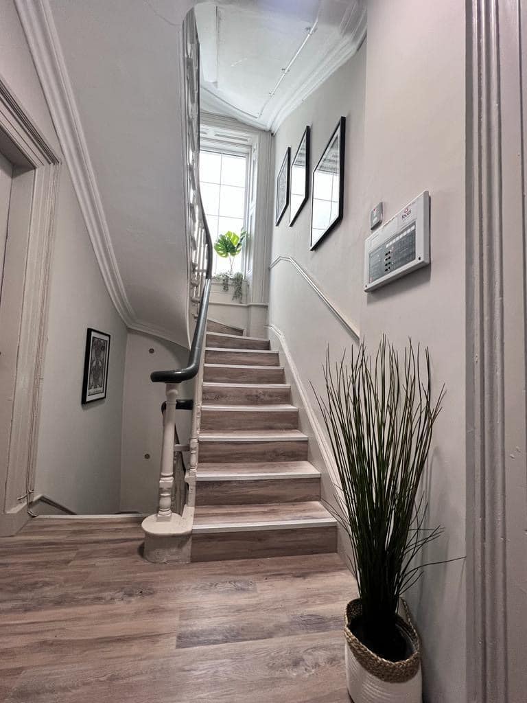 Staircase and landing with white banisters and timber-effect flooring at Kings House, Holywood.
